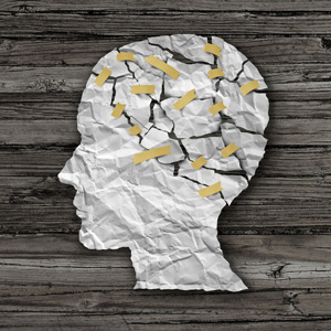 Brain disease therapy and mental health treatment concept as a sheet of torn crumpled white paper taped together as a human face on wood as a symbol for neurology surgery or psychological help.