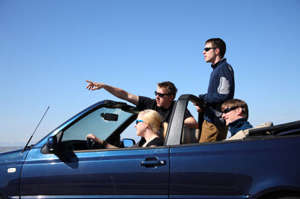 Photo shows an adolescent girl driving a convertible with three other adolescents