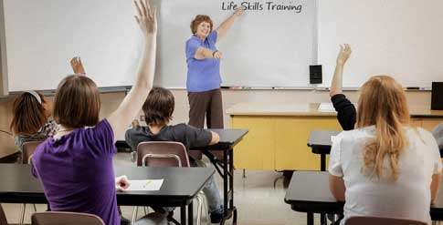 Teacher pointing at a white board at the front of a classroom
