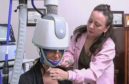Image of a provider putting a transcranial magnetic stimulation device on a woman’s head